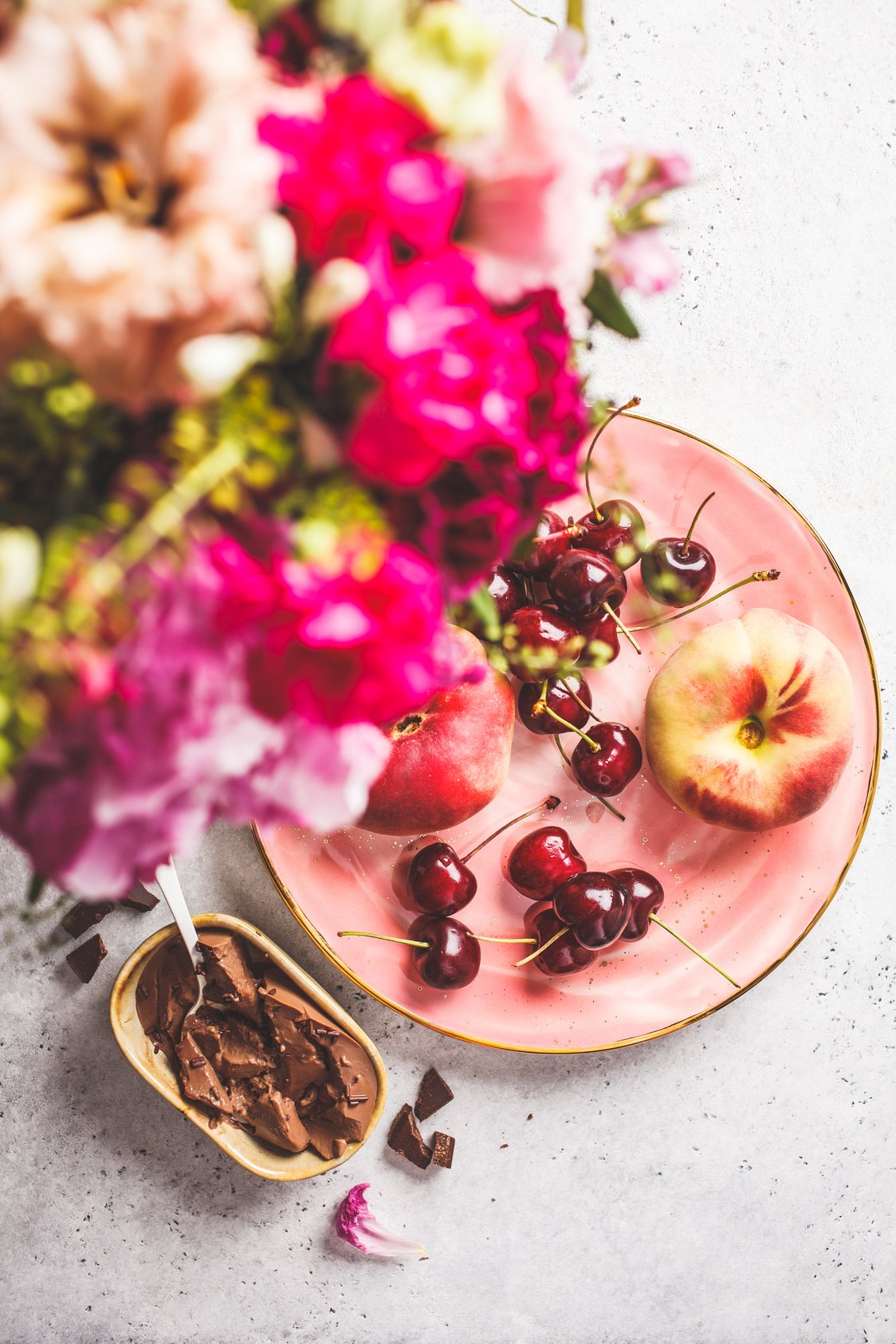 Beautiful pink food background. Flowers, chocolate dessert and berries on pink plate.